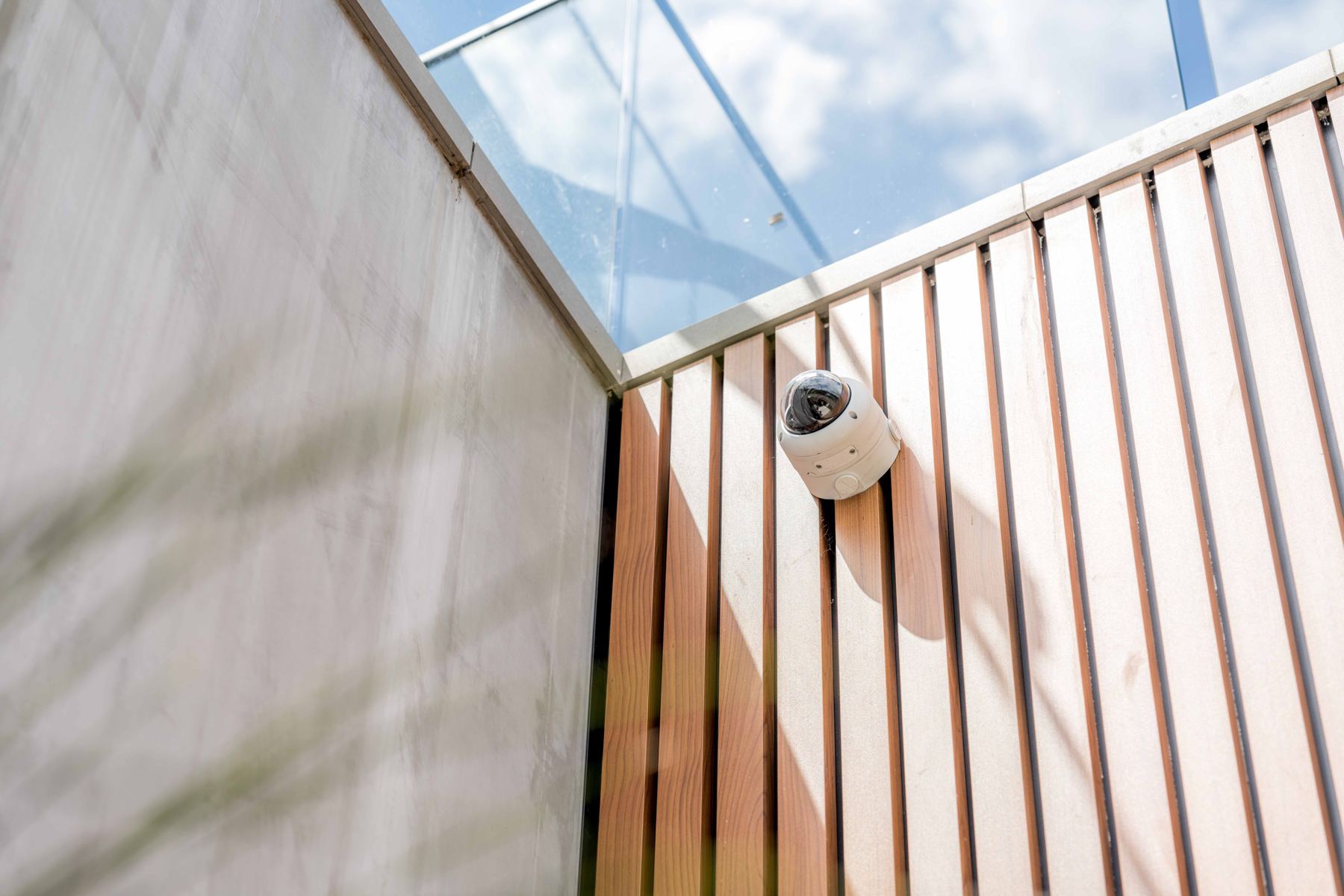 Dome security camera on a timber-battened wall